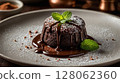 Delicious fondant cake with flowing chocolate and mint on a plate 128062360