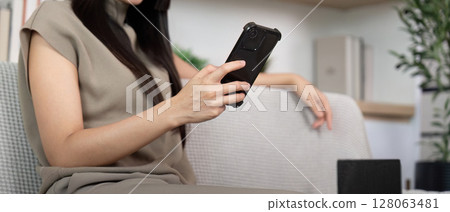 Digital Connection and Relaxation. Young woman browsing smartphone at home. Digital Connection and Relaxation. Young woman browsing smartphone at home. 128063481