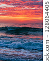 Vibrant Pink And Orange Sunrise Over Calm Ocean Waves 128064405