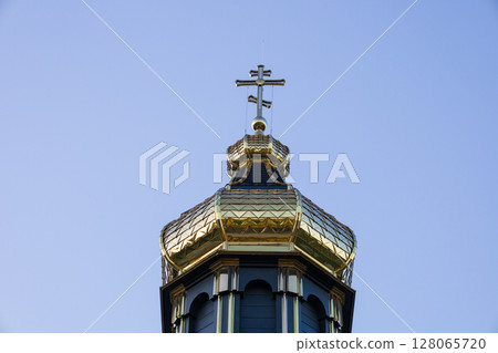 A stunning golden dome adorned with a cross rises above an old church, framed by a bright blue sky during a sunny day A stunning golden dome adorned with a cross rises above an old church, framed by a bright blue sky during a sunny day 128065720