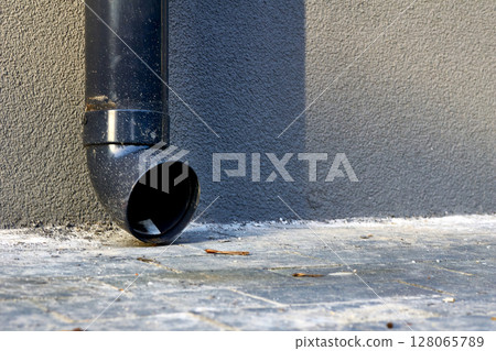Plastic drain pipe on a gray plastered wall.Rain runoff. Plastic drain pipe on a gray plastered wall.Rain runoff. 128065789