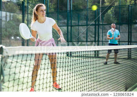 European woman padel tennis player trains on the outdoor court 128065824