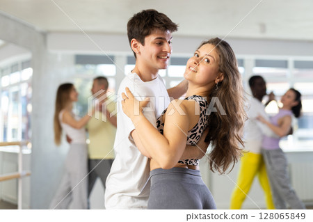 Young woman dances incendiary tango with man partner during choreography lesson 128065849