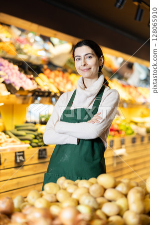 Young woman seller offering potatoes in vegetable shop 128065910