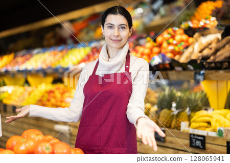 Female seller of fruit and vegetable store waits for visitors near counter 128065941