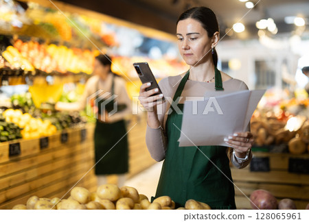 Woman salesman working with papers in store Woman salesman working with papers in store 128065961