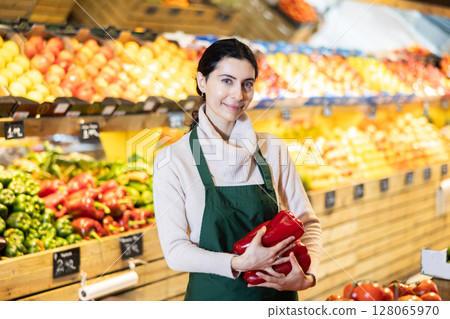 Woman seller offering bell peppers 128065970