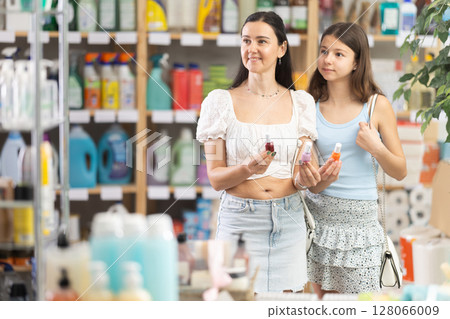 Happy mother and daughter in summer clothes choosing nail polish in supermarket 128066009