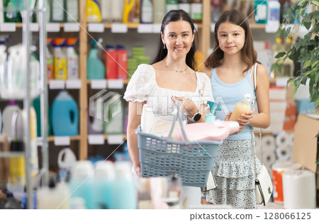Mother and daughter with full basket choosing something in supermarket 128066125