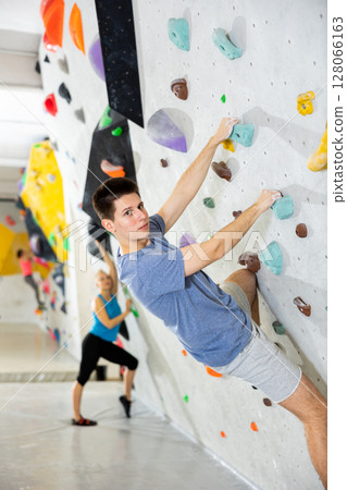 Man training at bouldering gym without special climbing equipment Man training at bouldering gym without special climbing equipment 128066163