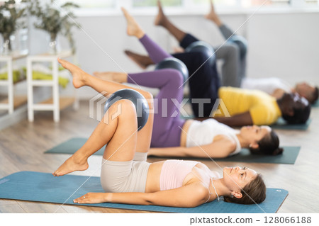 Girl coach shows students, holds fitball in lap and moves, shakes, shins, feet Girl coach shows students, holds fitball in lap and moves, shakes, shins, feet 128066188