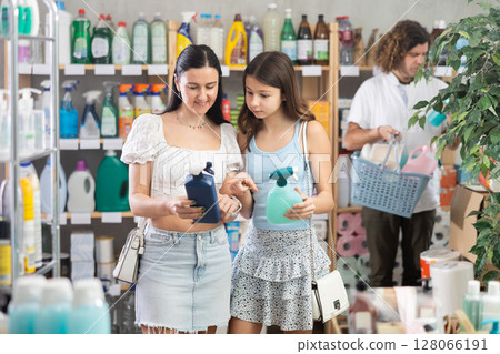 Woman with daughter choosing cleaning spray during family shopping 128066191
