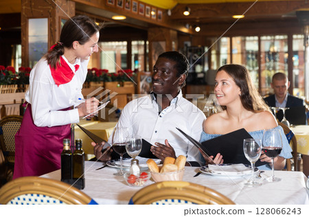 Positive young couple making order at restaurant Positive young couple making order at restaurant 128066243