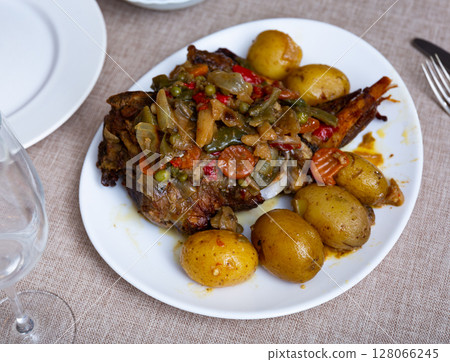 Chicken leg baked with vegetables served with side dish of boiled potatoes. Chicken leg baked with vegetables served with side dish of boiled potatoes. 128066245
