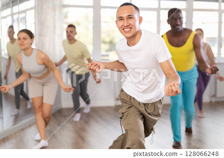 Asian guy practicing rhythmic aerobics during group workout 128066248