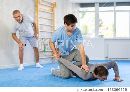 Guy practicing armlock in training bout during self-defence course 128066256