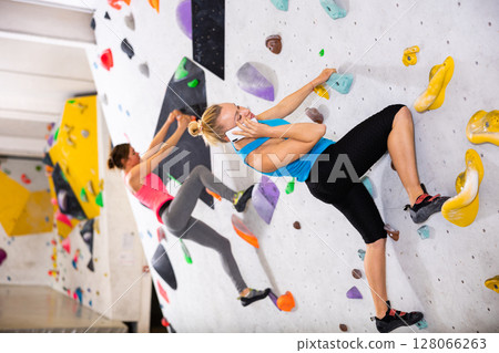 Woman having phone call during training in bouldering gym Woman having phone call during training in bouldering gym 128066263