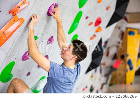 Man training at bouldering gym without special climbing equipment Man training at bouldering gym without special climbing equipment 128066269