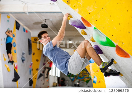 Young man exercising in climbing gym Young man exercising in climbing gym 128066276