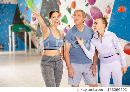 Adult and young women and adult man posing on climbing wall 128066302