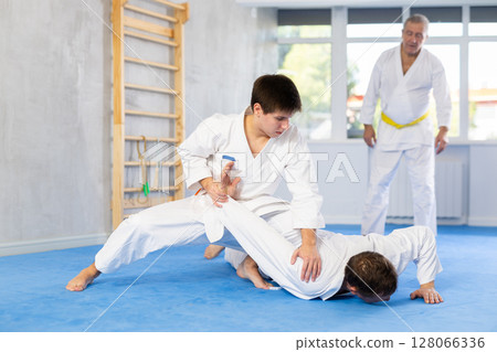 Adult and young men training judo fight Adult and young men training judo fight 128066336