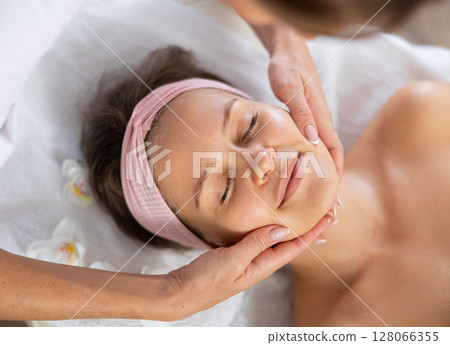 Young woman getting facial massage in salon Young woman getting facial massage in salon 128066355