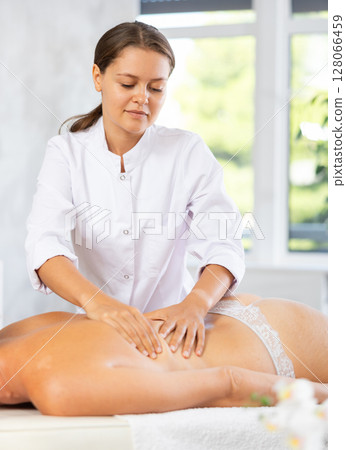 Young woman masseuse doing back massage Young woman masseuse doing back massage 128066459