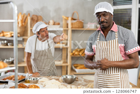 Disheartened African artisan baker scolded by partner in bakery 128066747