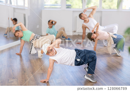 Dynamic happy boy training breakdance drops during workout session with group of children in studio Dynamic happy boy training breakdance drops during workout session with group of children in studio 128066789