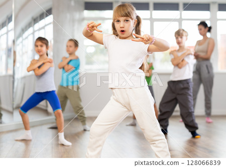 Girl learn to dance modern dances, doing movement with unrecognizable teacher. 128066839