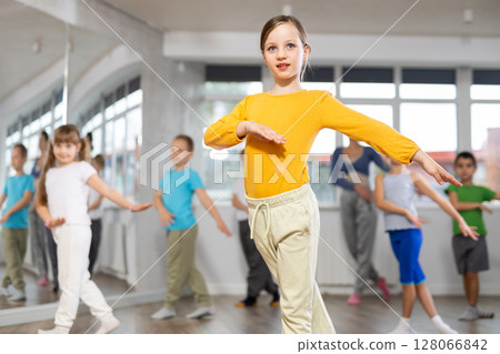 Girl learn to dance modern dances, doing movement with unrecognizable teacher. 128066842