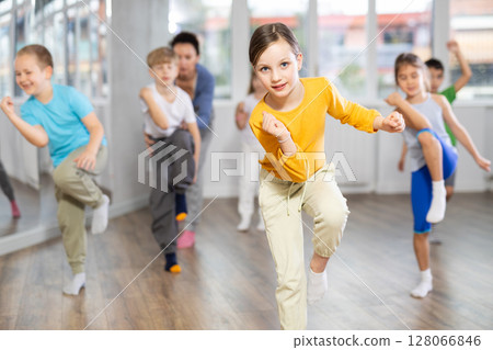 Children studying modern style dances with female teacher in dance class Children studying modern style dances with female teacher in dance class 128066846