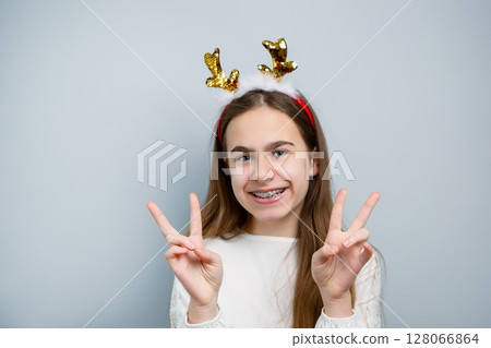 Cheerful girl reindeer antlers gray background showing different funny emotions, surprise, joy 128066864