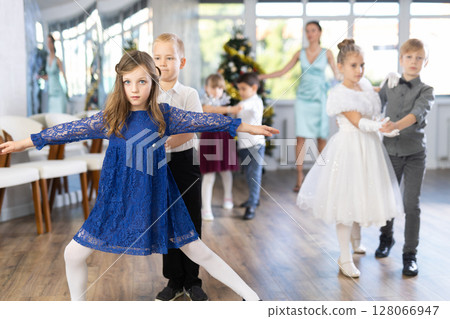 Little children practicing waltz dance in school-hall decorated with Christmas-tree Little children practicing waltz dance in school-hall decorated with Christmas-tree 128066947