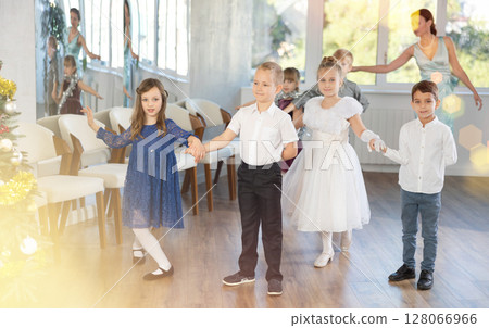 Christmas ball - group of children in festive clothes dances a waltz around New Year tree Christmas ball - group of children in festive clothes dances a waltz around New Year tree 128066966