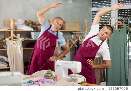 Male tailors doing a warm-up at work 128067026