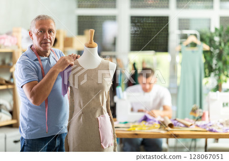 Mature tailor working with mannequin against the background of specialist 128067051