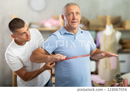 Young Tailor Taking Measurements From Elderly Man 128067056