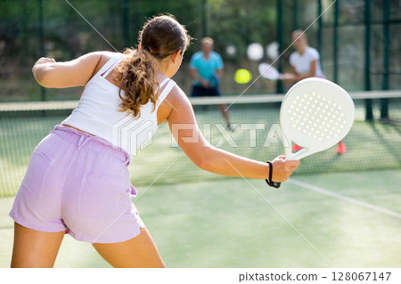 Woman playing padel tennis match during training on court 128067147