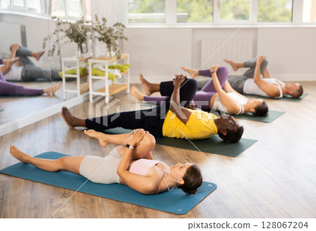 Young woman performing Eka Pada Apanasana in yoga class 128067204