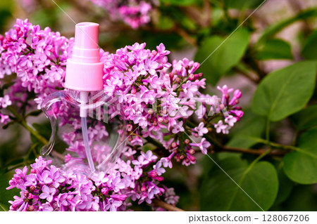 Cosmetic pink atomizer spray among delicate purple lilac flowers Cosmetic pink atomizer spray among delicate purple lilac flowers 128067206