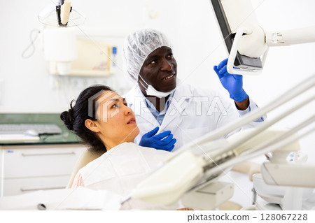 Male dentist shows the female patient the result of dental x-ray 128067228