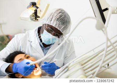 Closeup view of dentist treating teeth of woman in dentist office Closeup view of dentist treating teeth of woman in dentist office 128067242