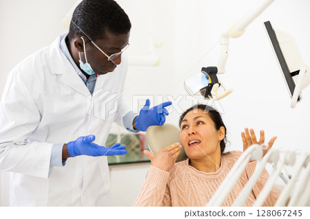 Dissatisfied woman talking to confused dentist after dental treatment 128067245