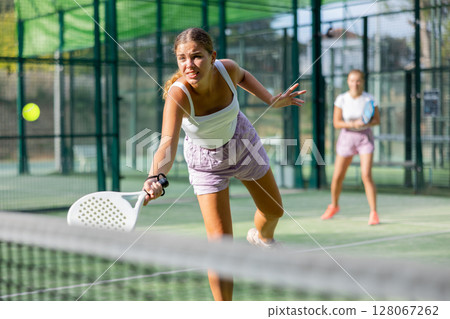 Young woman padel tennis player trains on the outdoor court 128067262