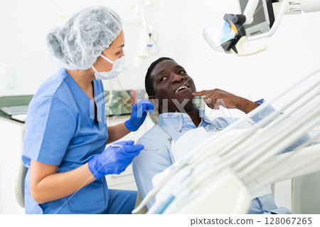 Patient complaining to female dentist about toothache at dental office Patient complaining to female dentist about toothache at dental office 128067265