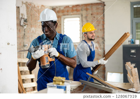 Two builders working on indoor construction site 128067319