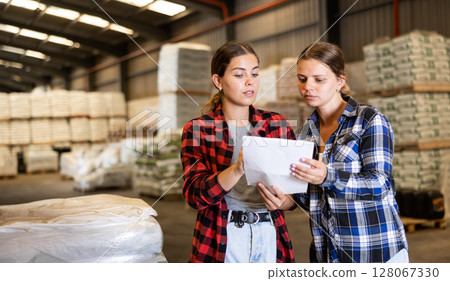 Female warehouse owner and manager keep track of products in warehouse Female warehouse owner and manager keep track of products in warehouse 128067330