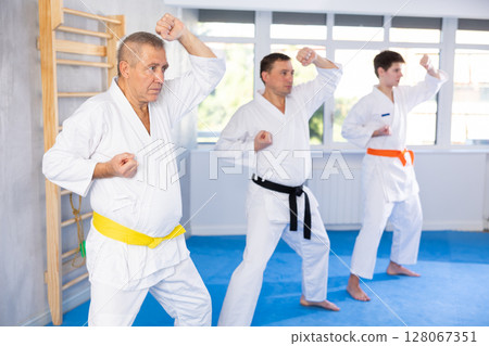 Mature man with other athletes of different ages during karate or judo classes 128067351