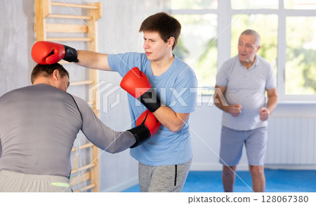 Guy getting blow to body in boxing sparring at self-defense training 128067380